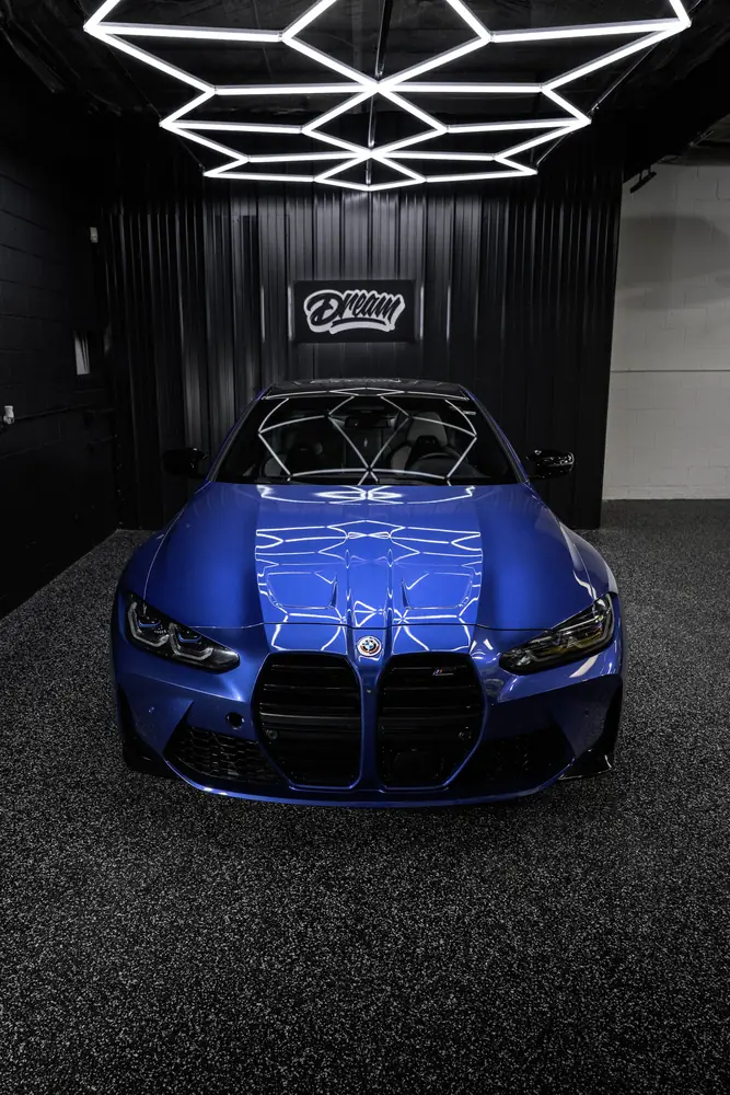 Blue BMW M4 with the hex ceiling reflected sharply across the hood