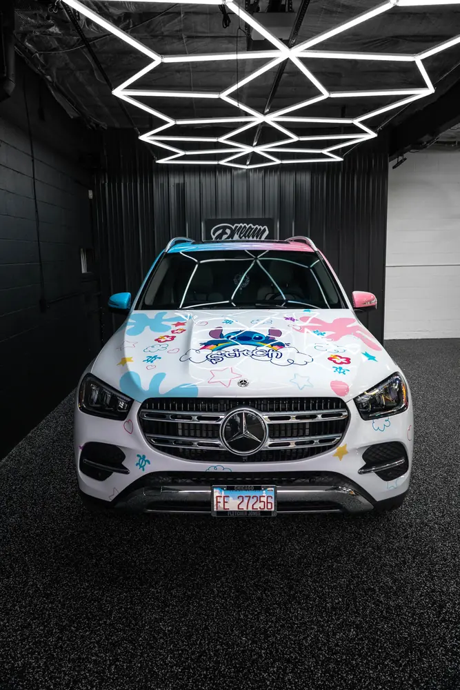 White Mercedes GLE with a custom printed Stitch-themed wrap in the hex-lit bay